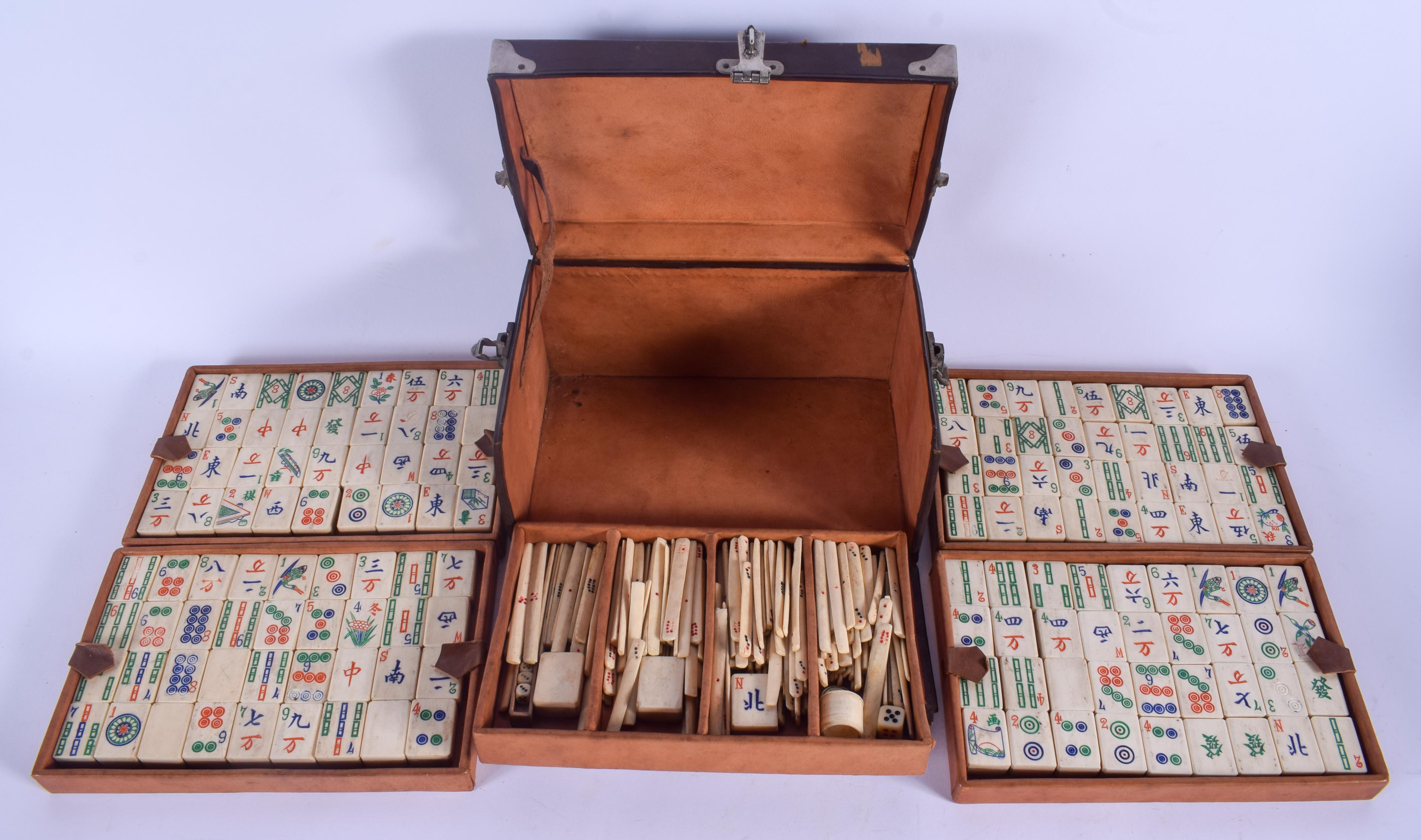 A VINTAGE CHINESE LEATHER CASED BAMBOO AND BONE MAHJONG SET with white metal mounts. 24 cm x 13 cm.