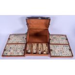 A VINTAGE CHINESE LEATHER CASED BAMBOO AND BONE MAHJONG SET with white metal mounts. 24 cm x 13 cm.