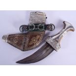 A 19TH CENTURY MIDDLE EASTERN OMANI CARVED RHINOCEROS HORN HANDLED JAMBIYA DAGGER overlaid in silver