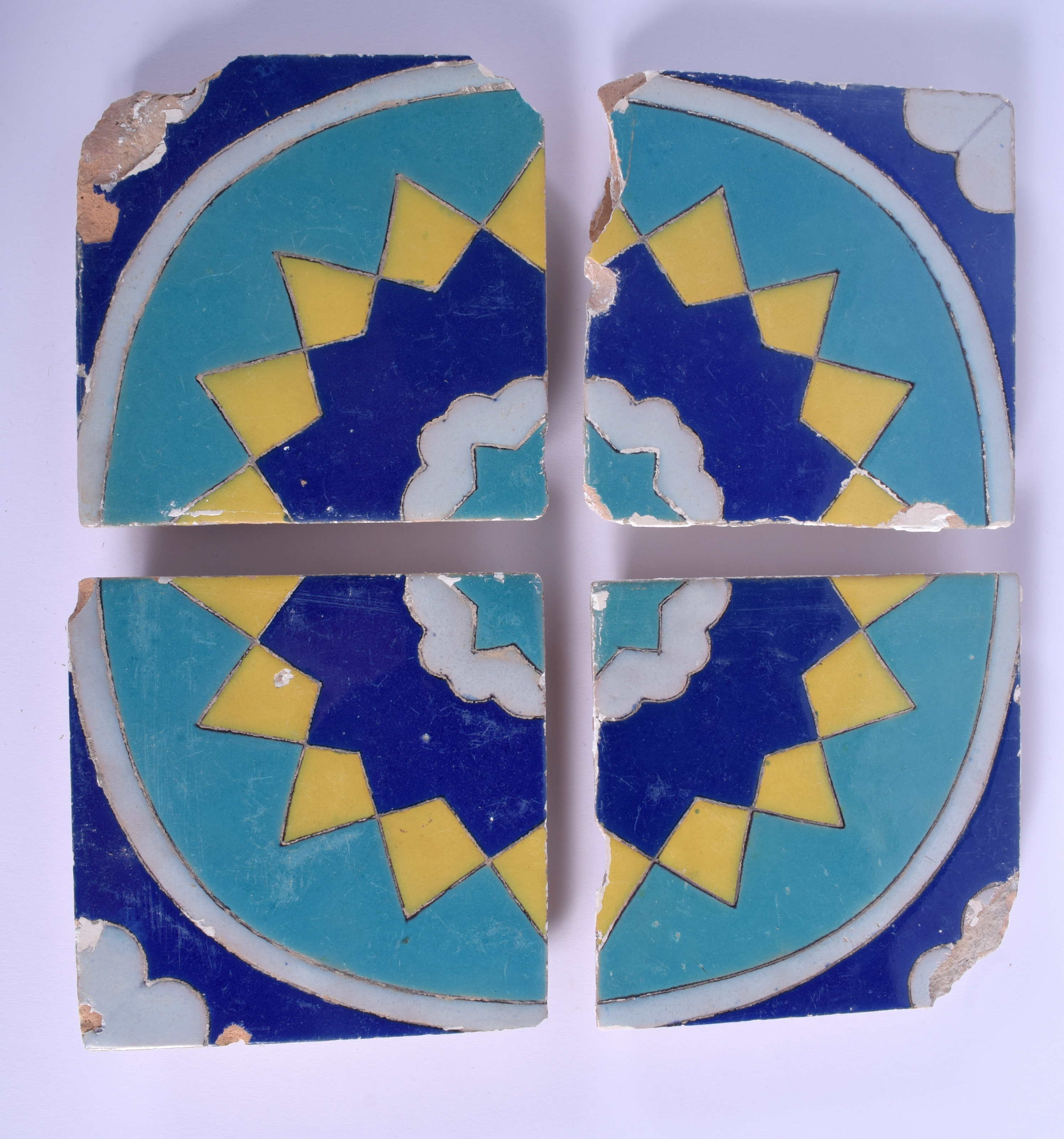 A SET OF FOUR MIDDLE EASTERN MULTAN BLUE AND YELLOW GLAZED TILES. Each 15 cm square. (4)