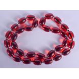 A CHERRY AMBER TYPE NECKLACE. 206 grams. 94 cm long, largest bead 2.5 cm x 1.5 cm.