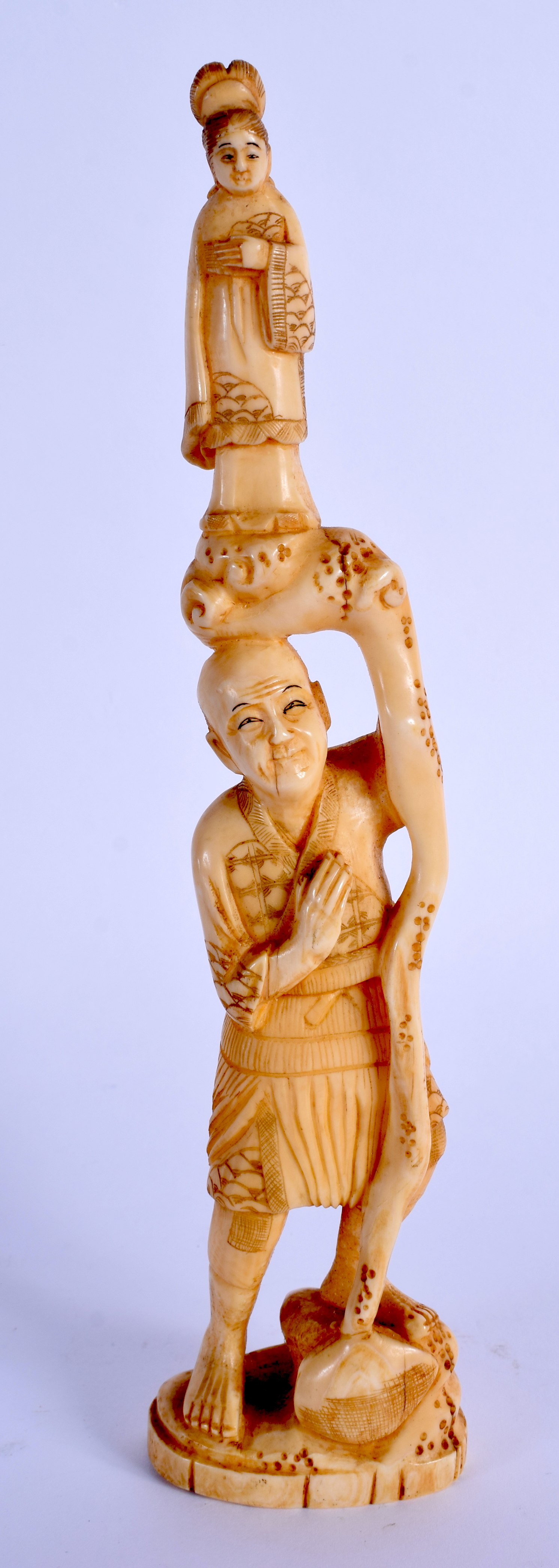 A 19TH CENTURY JAPANESE MEIJI PERIOD CARVED IVORY OKIMONO modelled holding aloft a female. 23.5 cm h