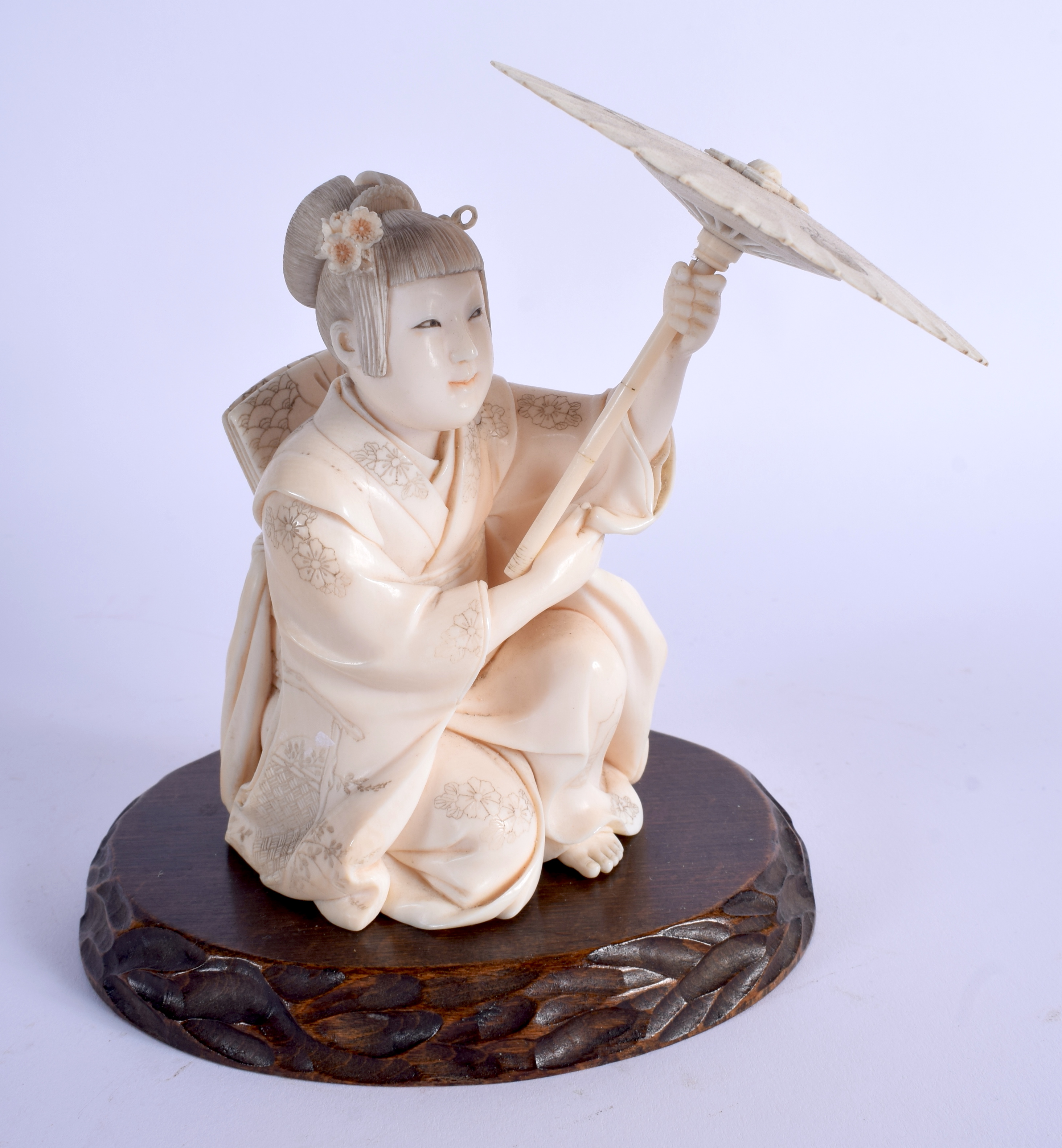 A FINE 19TH CENTURY JAPANESE MEIJI PERIOD CARVED IVORY OKIMONO modelled as a female sheltering under