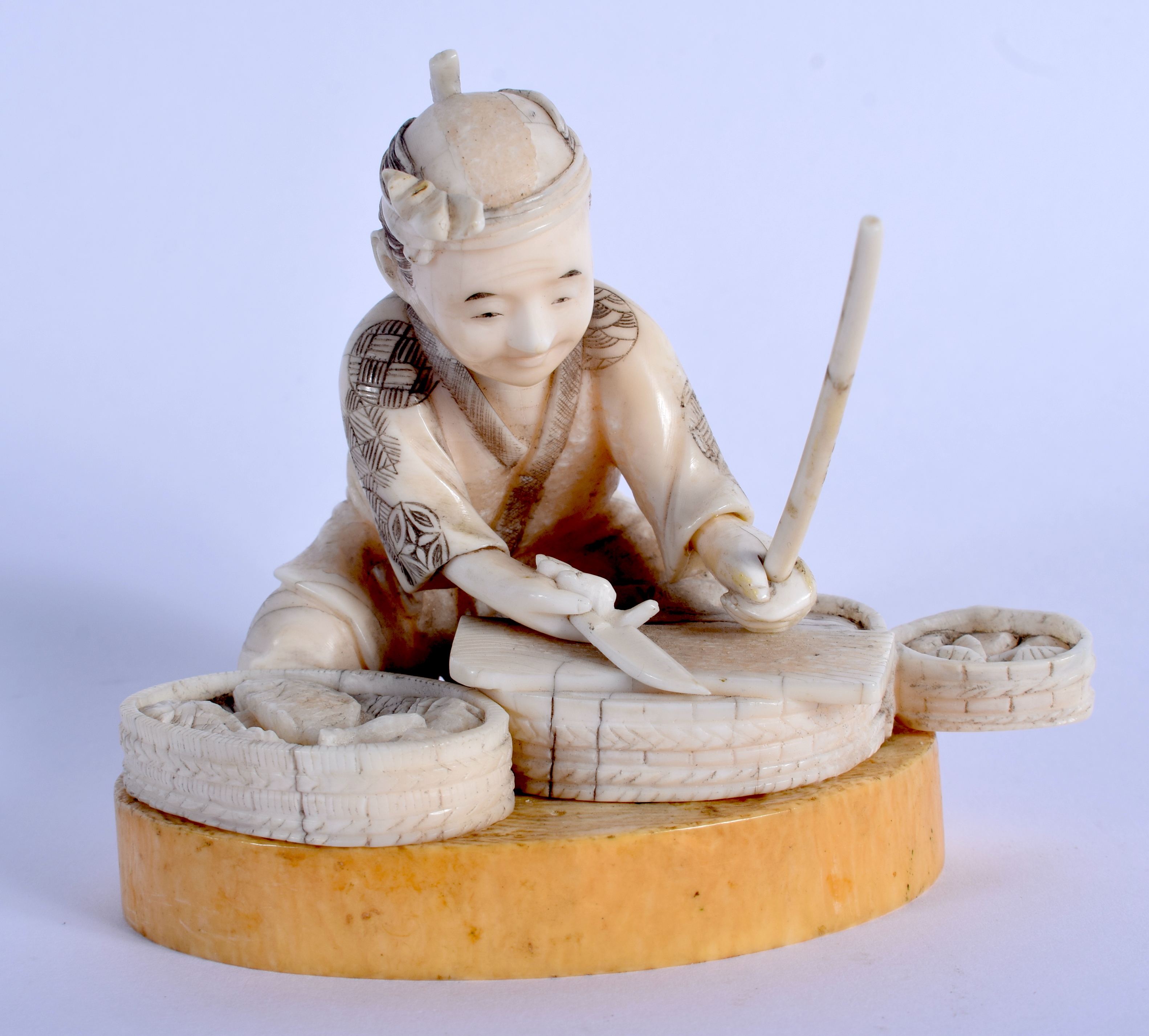 A 19TH CENTURY JAPANESE MEIJI PERIOD CARVED BONE FIGURE OF A MALE modelled preparing fish. 8 cm x 9