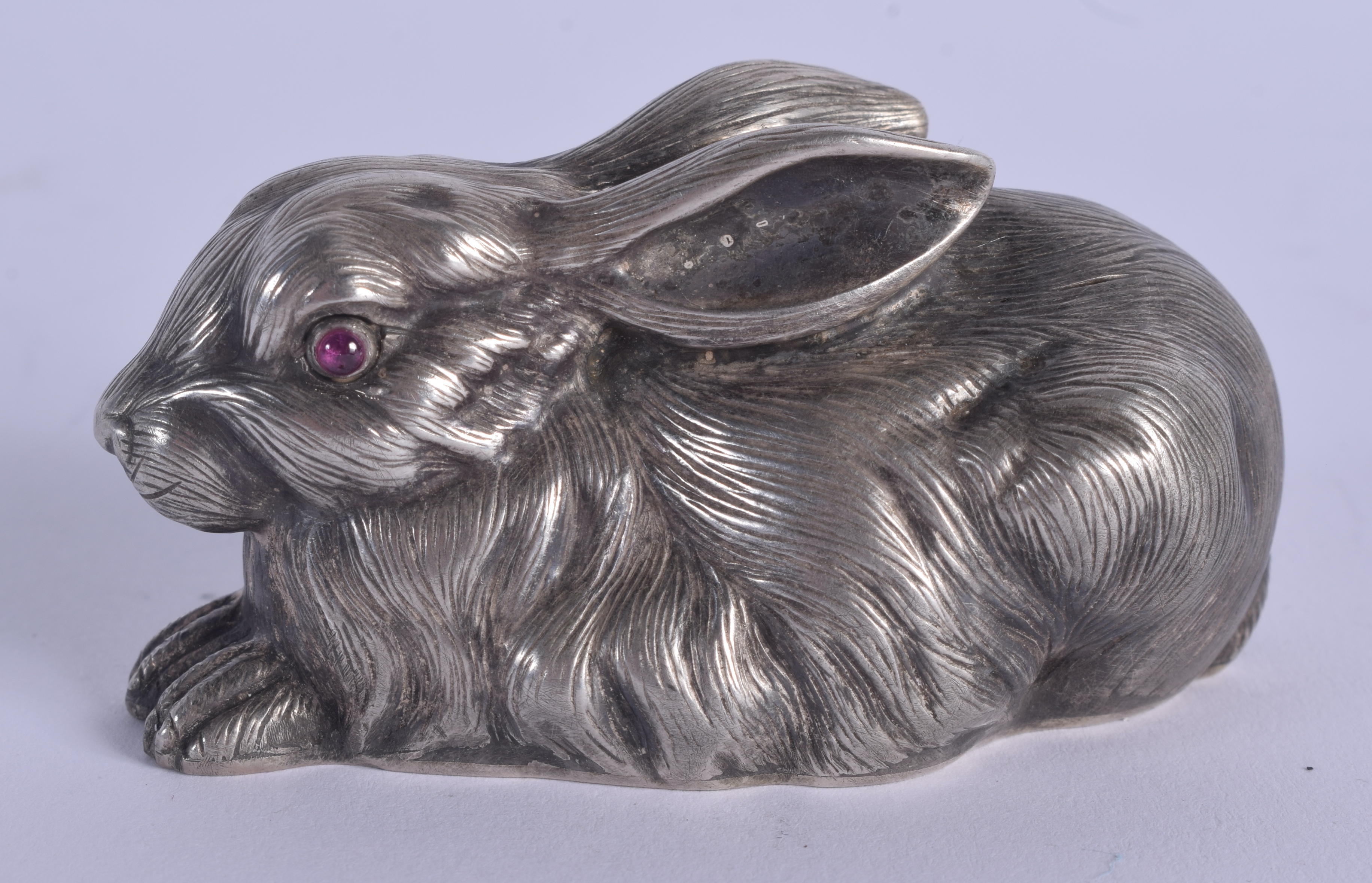 A CONTINENTAL SILVER AND RUBY EYED FIGURE OF A RABBIT. 53 grams. 5.5 cm x 3 cm.