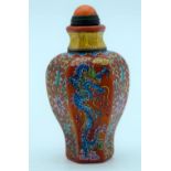 A Chinese red ground snuff bottle with a dragon and foliage. 9cm.