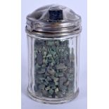 A COLLECTION OF ROUGH CUT EMERALDS within a silver topped jar. (qty)