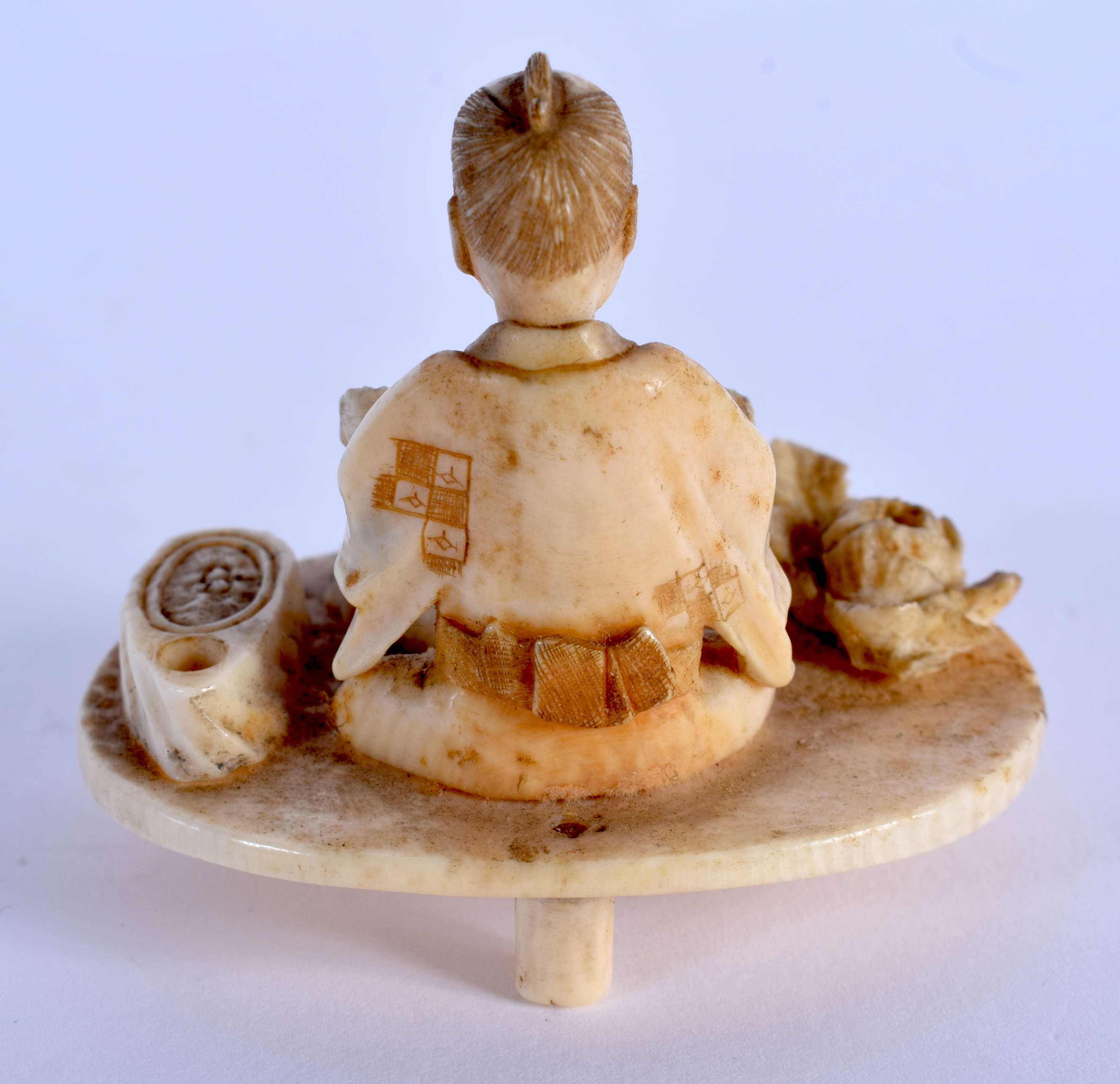 A 19TH CENTURY JAPANESE MEIJI PERIOD CARVED IVORY OKIMONO modelled as a male on a table. 5.5 cm x 5 - Image 2 of 3