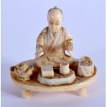 A 19TH CENTURY JAPANESE MEIJI PERIOD CARVED IVORY OKIMONO modelled as a male on a table. 5.5 cm x 5