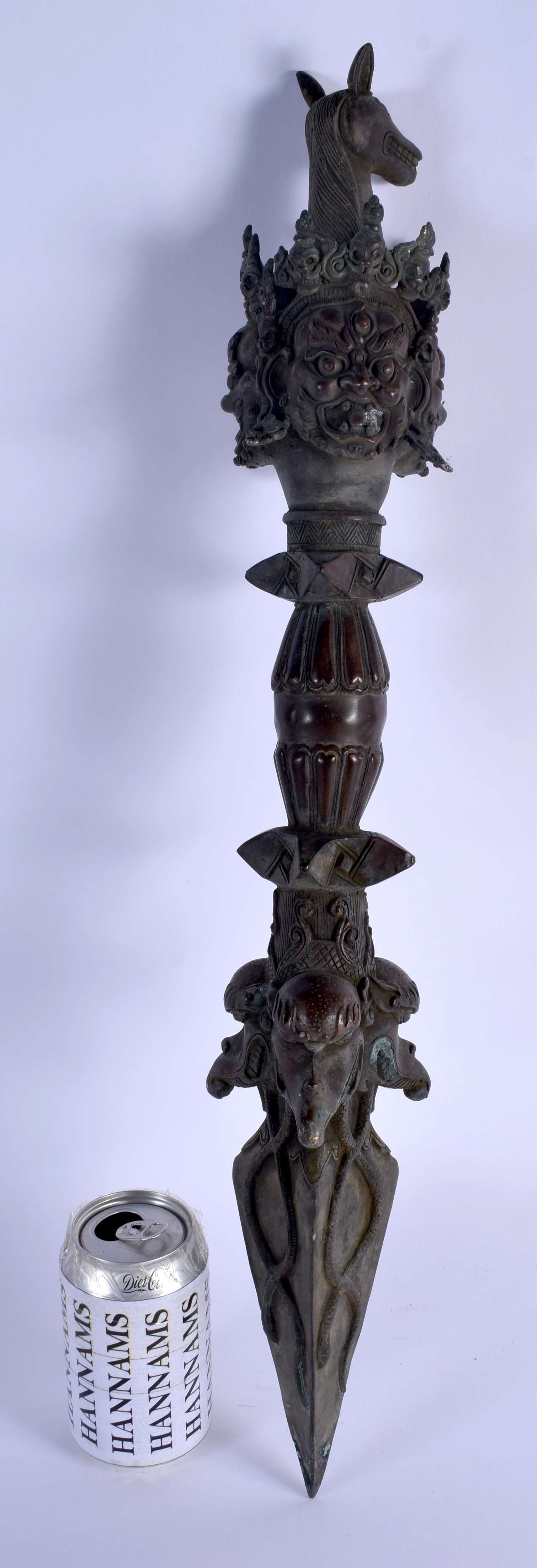 A LARGE CHINESE TIBETAN BRONZE PHURBA modelled with buddhistic mask heads. 60 cm long.