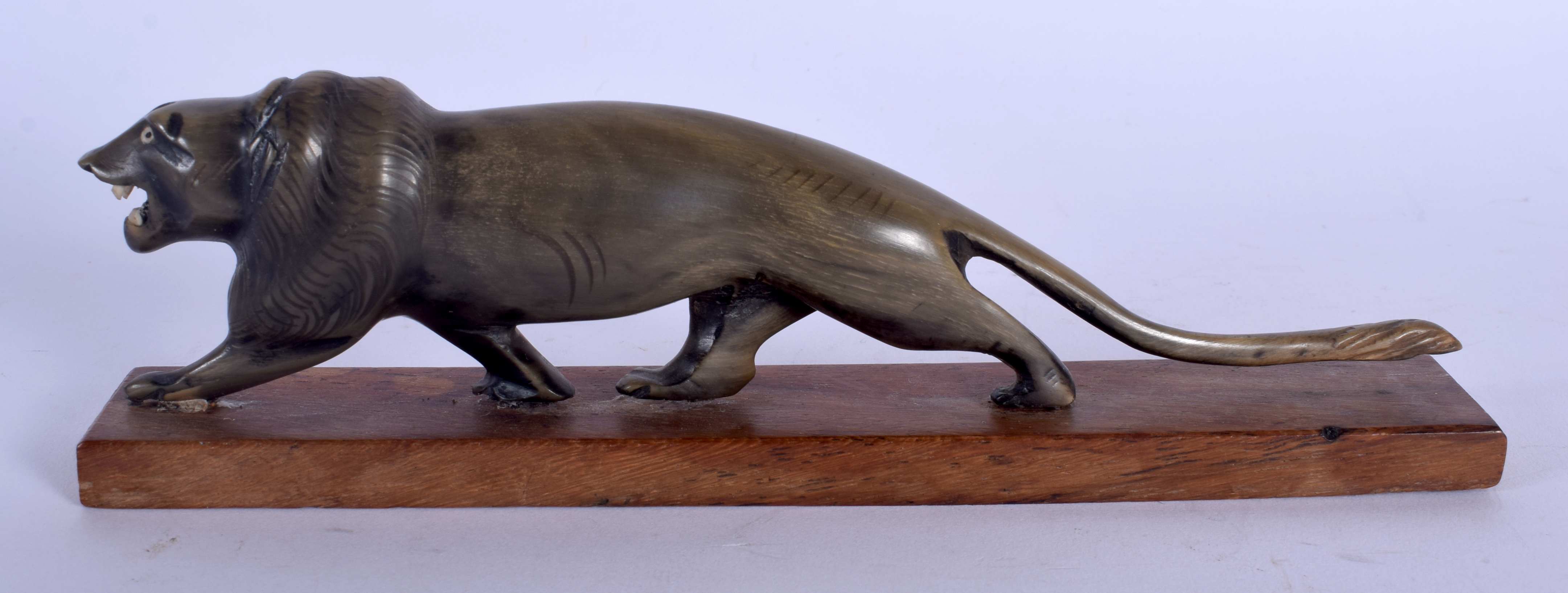 A 19TH CENTURY MIDDLE EASTERN CARVED RHINOCEROS HORN FIGURE OF A ROAMING LION modelled upon a wooden