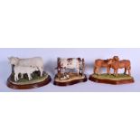 A GROUP OF THREE BORDER FINE ARTS FIGURES OF COWS upon wooden plinths. Largest 20 cm x 15 cm. (3)