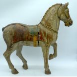 AN EARLY 20TH CENTURY INDO PERSIAN POLYCHROMED WOOD FIGURE OF A HORSE modelled with one leg raised.