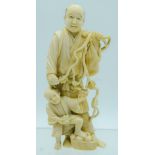 A 19TH CENTURY JAPANESE MEIJI PERIOD CARVED IVORY OKIMONO modelled as a figure and a child picking f