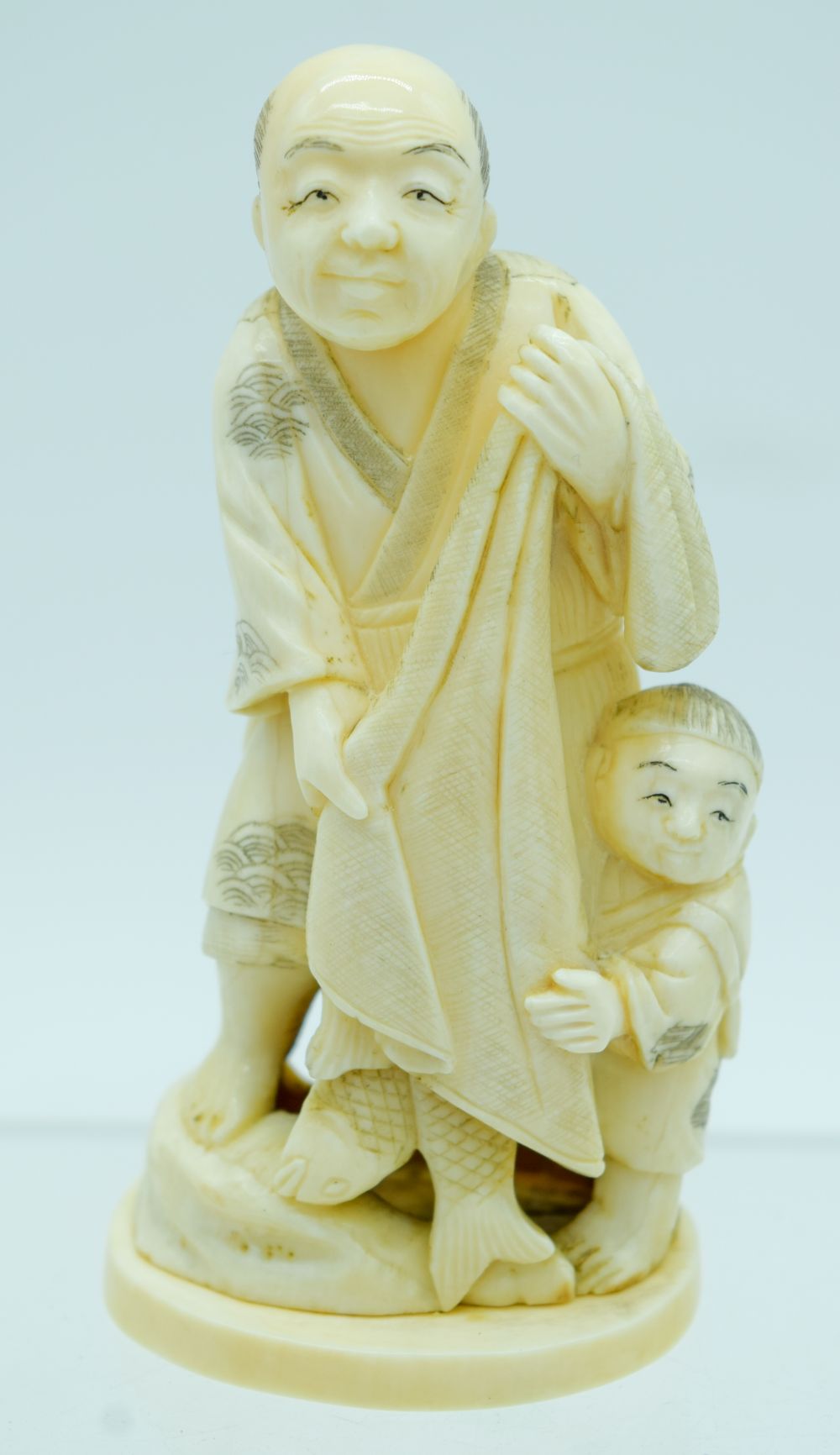 A 19TH CENTURY JAPANESE MEIJI PERIOD CARVED IVORY OKIMONO modelled as a father and son. 10 cm high.