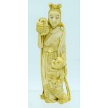 A 19TH CENTURY JAPANESE MEIJI PERIOD CARVED IVORY OKIMONO modelled as a sanding female with boy. 18