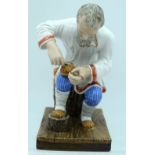 A 19TH CENTURY RUSSIAN PORCELAIN FIGURE OF A BAST SHOE MAKER Popov Factory, modelled sitting on a tr