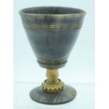 A 19TH CENTURY GERMAN CARVED RHINOCEROS HORN GOBLET with dimpled stem and blond Rhinoceros