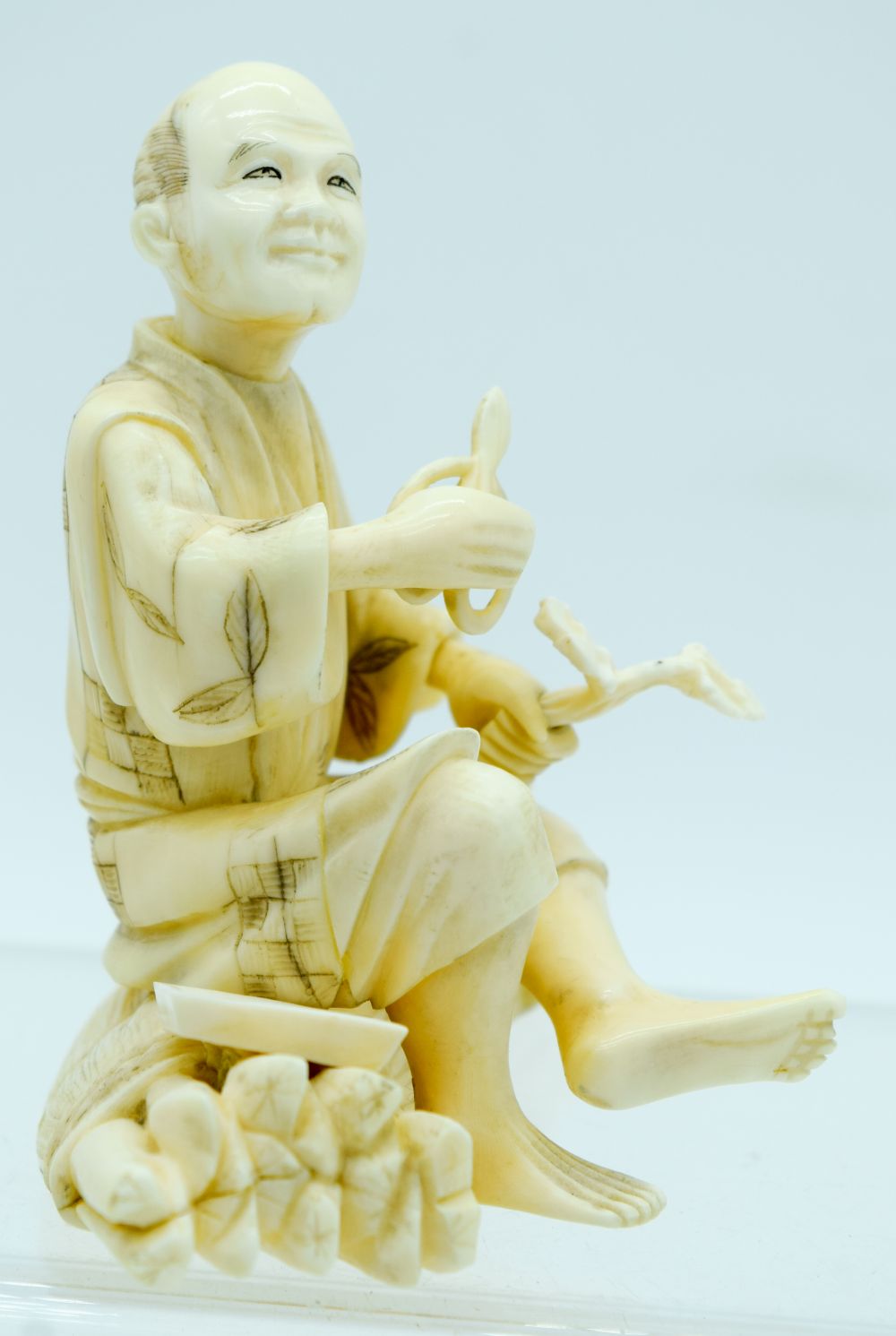 A 19TH CENTURY JAPANESE MEIJI PERIOD CARVED IVORY OKIMONO modelled as a male upon logs holding veget - Bild 4 aus 7