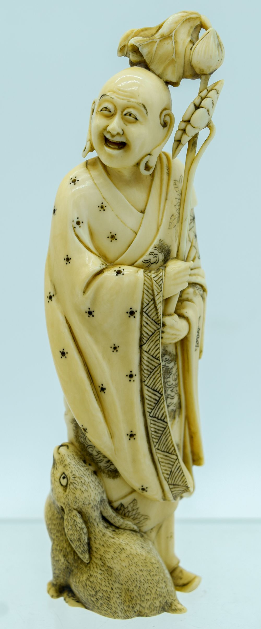 A 19TH CENTURY JAPANESE MEIJI PERIOD CARVED IVORY OKIMONO modelled as a buddha and a hare. 17 cm hig