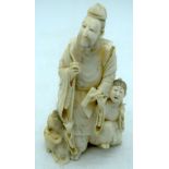 A 19TH CENTURY JAPANESE MEIJI PERIOD CARVED IVORY OKIMONO modelled standing beside two children. 23