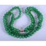 AN 18CT GOLD CARVED GREEN JADEITE NECKLACE 20th Century. Each strand 60 cm long.