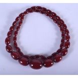 A 1930S CHERRY AMBER NECKLACE. 61 grams. 76 cm long, largest bead 2.75 cm wide.