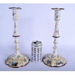 A RARE PAIR OF 18TH CENTURY ENGLISH BATTERSEA ENAMEL CANDLESTICKS painted with romantic figures, fol