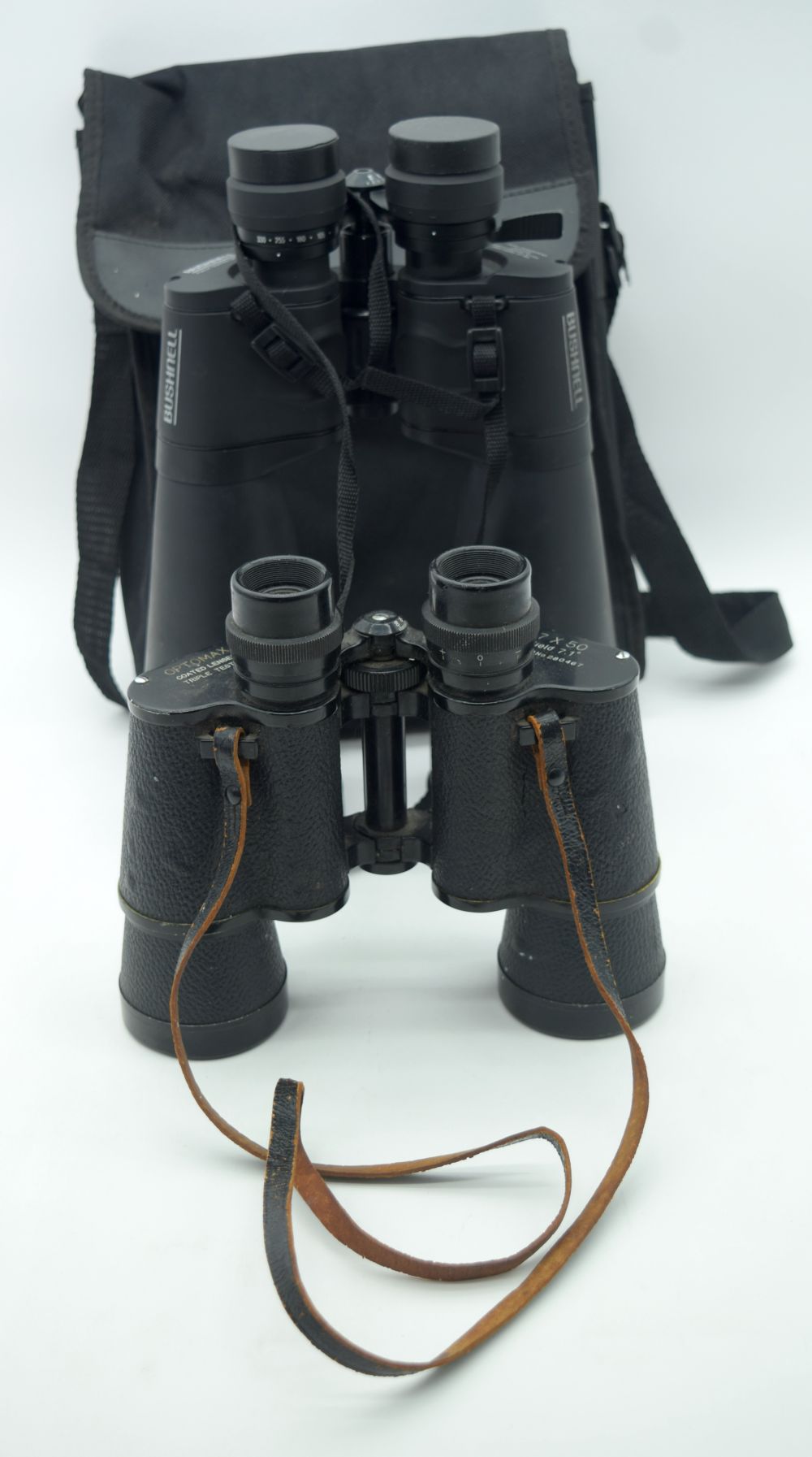 A pair of Bushnell binoculars together with a set of Optimax binoculars. 30cm (2).