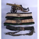 TWO ANTIQUE BELTS possibly military, together with a cast iron painted cannon. Largest 40 cm long. (