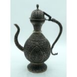 An Islamic white metal coffee pot heavily embossed with foliage and snake handle. 36cm.