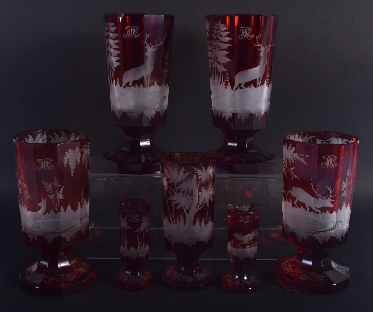 SEVEN ANTIQUE BOHEMIAN RUBY GLASS GOBLET BEAKERS decorated with deer. Largest 18.5 cm high. (7)