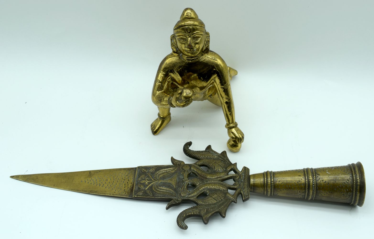 An Indian Bronze figure of a crouching male together with an embossed brass staff head. 39 (2).