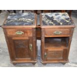 A pair of Edwardian carved panel Oak bedside cabinets with a porcelain cooling box and marble tops.