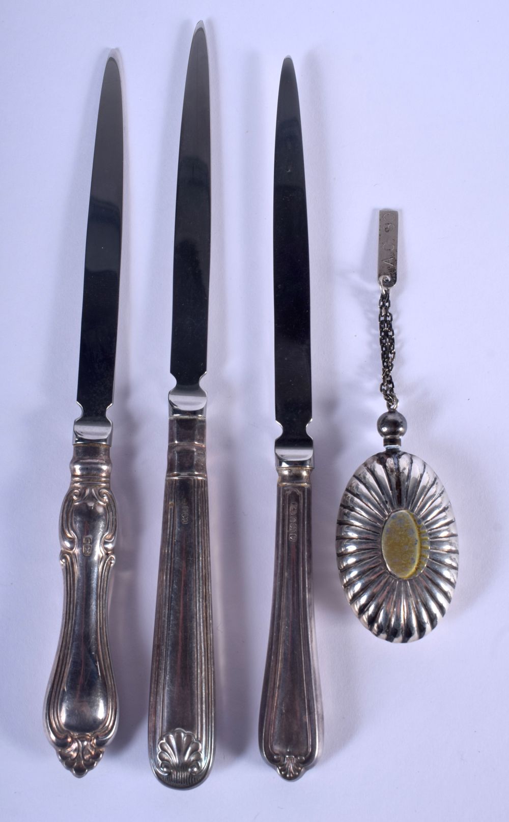 THREE SILVER HANDLED PAPER KNIVES and a white metal perfume flask. Largest 18 cm long. (4)