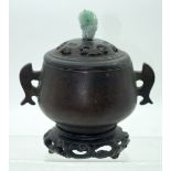A Chinese bronze lidded Incense burner with a Jadeite handle on a hardwood lid on a hardwood stand.