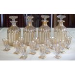 A SET OF FOUR 19TH CENTURY BOHEMIAN CLEAR AND GILDED LIQUOR DECANTERS AND STOPPERS together with mat