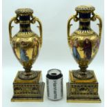 A LARGE PAIR OF EARLY 20TH CENTURY VIENNA TWIN HANDLED PORCELAIN PEDESTAL VASES painted with classic