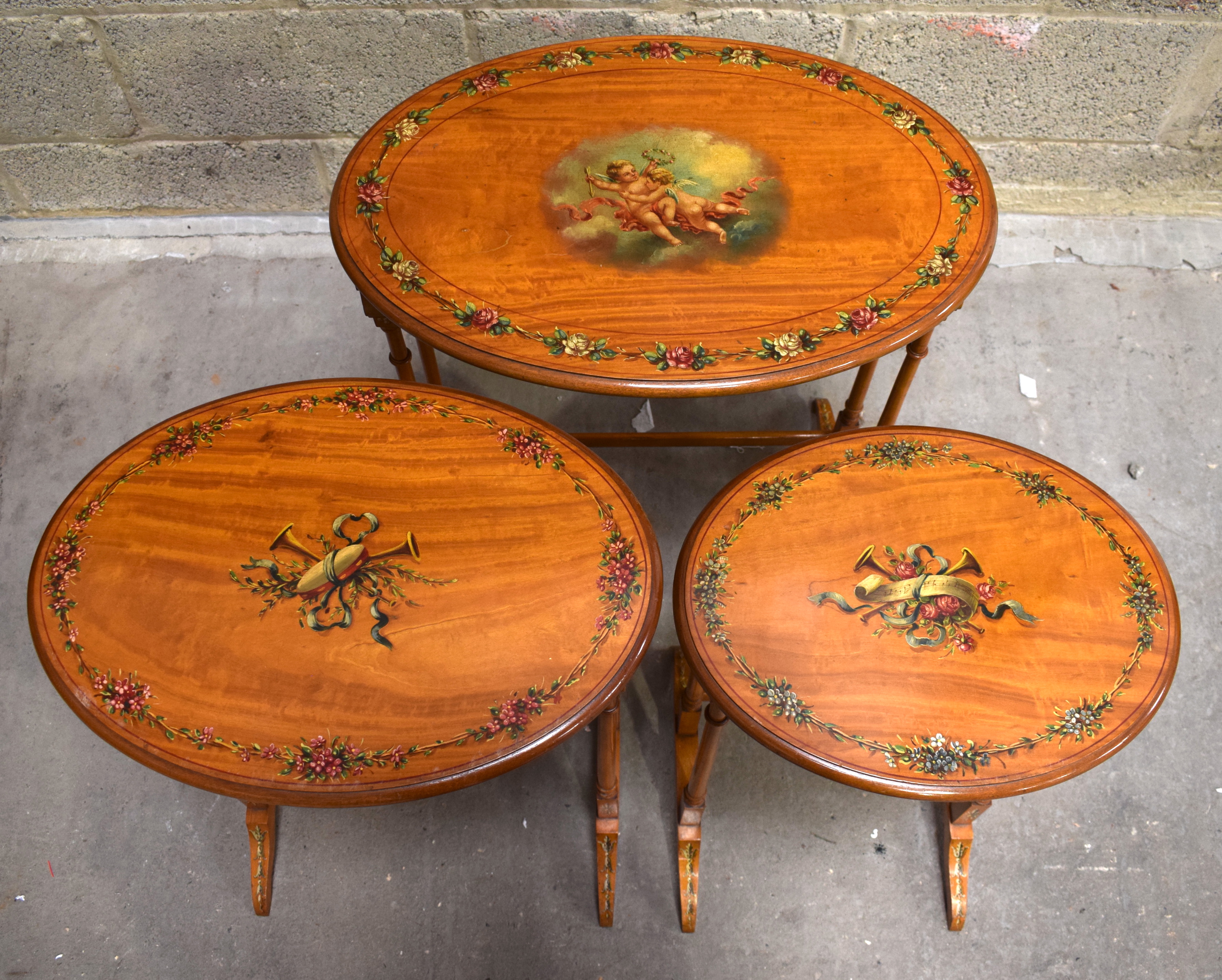 A NEST OF THREE EDWARDIAN PAINTED SATINWOOD TABLES decorated with putti in flight. Largest 57 cm x 6 - Image 3 of 4