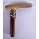 A 19TH CENTURY MIDDLE EASTERN CARVED RHINOCEROS HORN CANE HANDLE with wood shaft. 12 cm x 10 cm.