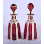 A PAIR OF 19TH CENTURY BOHEMIAN RUBY ENAMELLED GLASS LIQUOR BOTTLES AND STOPPERS decorated with gilt