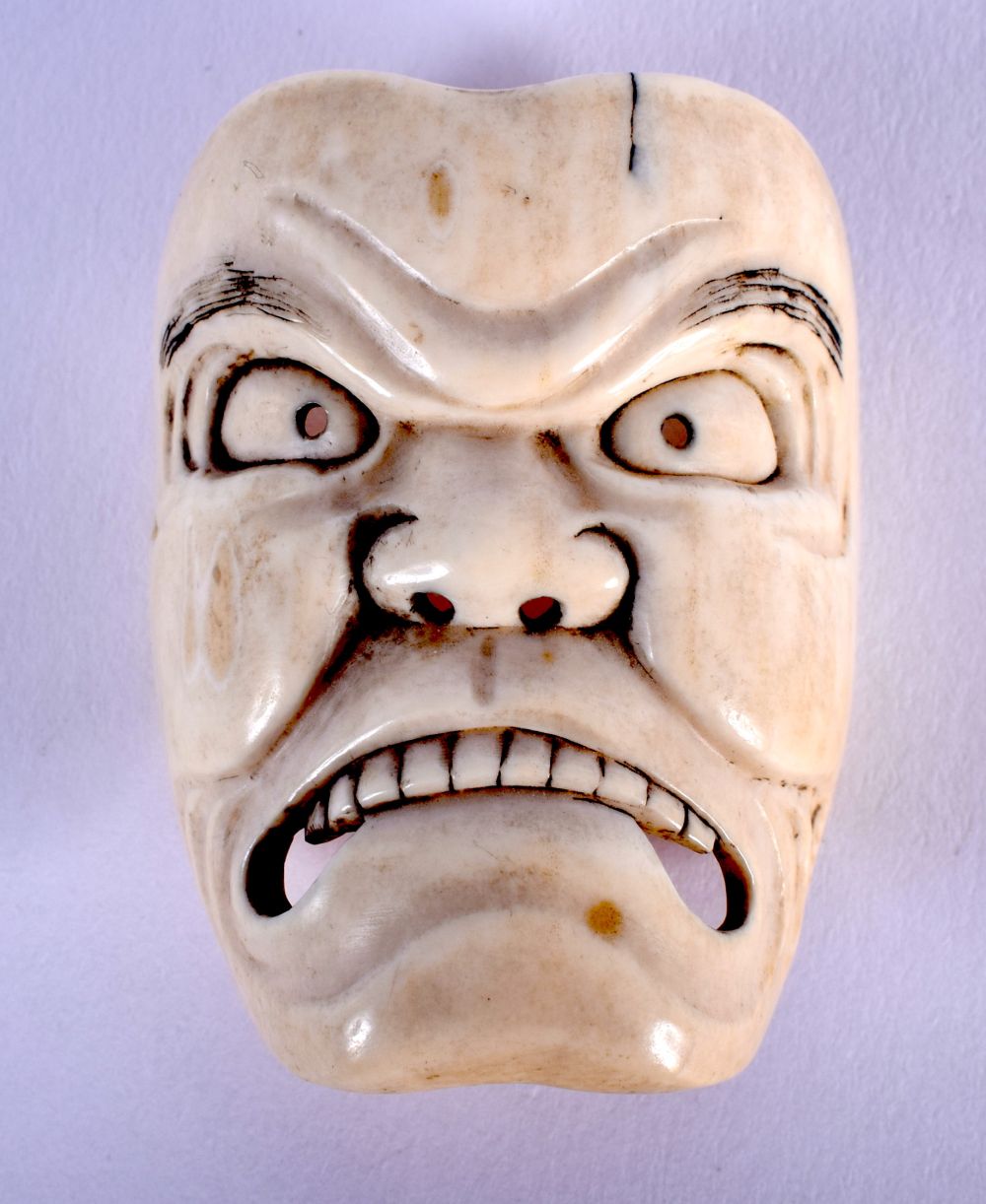 A 19TH CENTURY JAPANESE MEIJI PERIOD CARVED IVORY NOH MASK modelled as a scowling face. 4.5 cm x 3.5