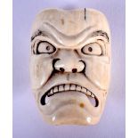 A 19TH CENTURY JAPANESE MEIJI PERIOD CARVED IVORY NOH MASK modelled as a scowling face. 4.5 cm x 3.5
