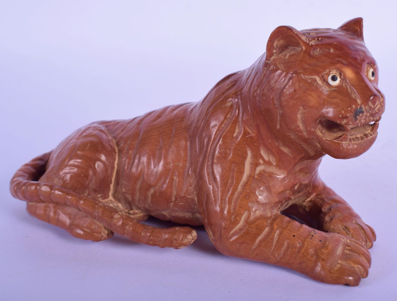 A JAPANESE CARVED BOXWOOD FIGURE OF A TIGER modelled recumbent. 13 cm x 8 cm.