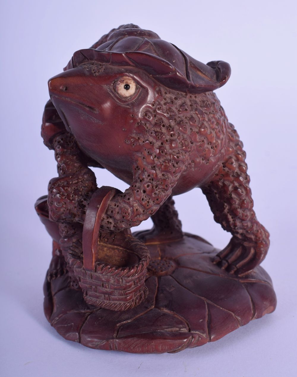 A JAPANESE CARVED BOXWOOD FIGURE OF A TOAD overlaid with a lotus flower. 10 cm x 6 cm.