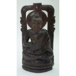 A carved hardwood South East Asian seated Buddha on a shrine. 30cm.