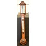 AN ANTIQUE OAK ANEROID BAROMETER with enamelled thermometer and oak capped motifs. 102 cm high.