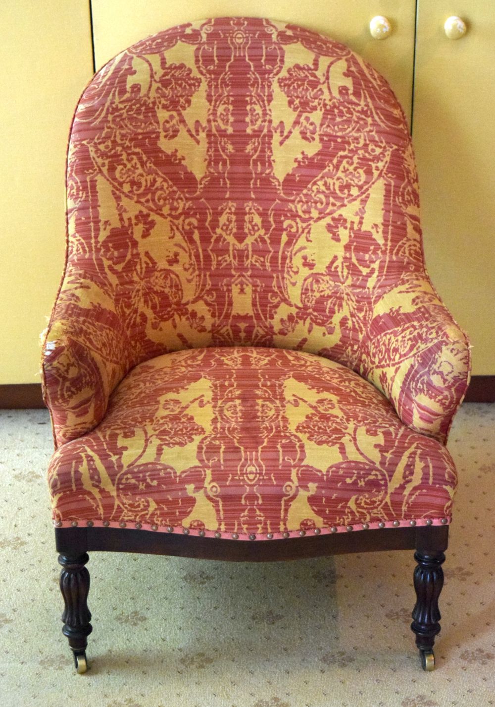 A VICTORIAN UPHOLSTERED ARM CHAIR with rectangular frieze and card legs. 90 cm x 60 cm.