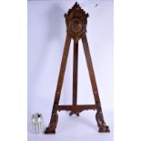 A LARGE 19TH CENTURY ARTS AND CRAFTS OAK STRUT EASEL carved with a central roundel and fish feet. 65