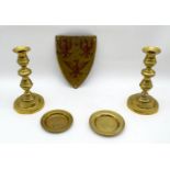 A pair of brass candlesticks together with two small brass dishes and a metal Griffin shield .20 cm